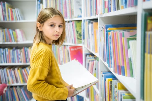Schoolgirl choosing book in school library.