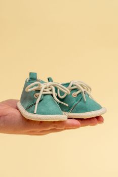 Womens hands hold a pair of tiny childrens shoes. As a symbol of motherhood and the expectation of