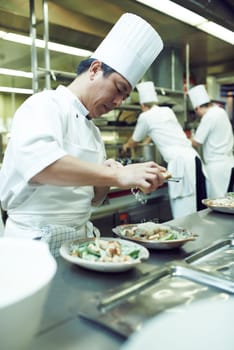 Plating up for service. chefs preparing a meal service in a professional kitchen.
