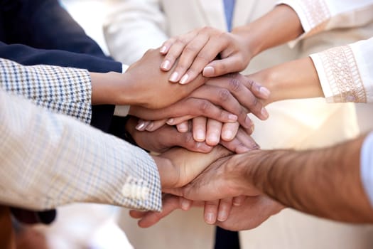 We support each others journeys. a group of unrecognizable businesspeople stacking their hands.