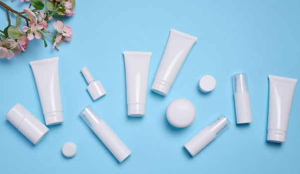 White plastic tubes, jars, and containers for cosmetic products on a blue background, advertising and branding of products
