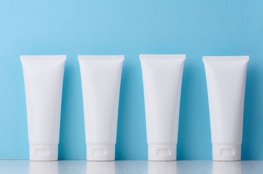 White plastic tubes for cosmetic products on a blue background, advertising and branding of products