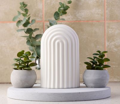 Ceramic pot with a plant and a white decorative arch on the table.