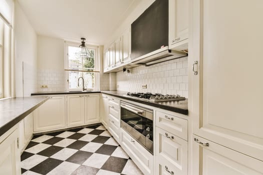 a kitchen with white cabinets and black and white tile