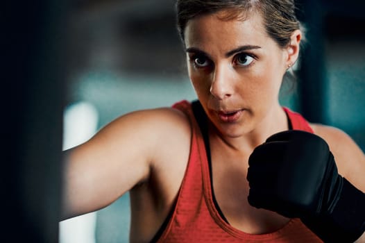 You can be both feminine and a fighter. an attractive young female kickboxer working out in the gym.