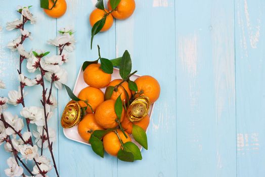 Flat lay Chinese new year tangerine oranges and plum blossoms on wooden table top.