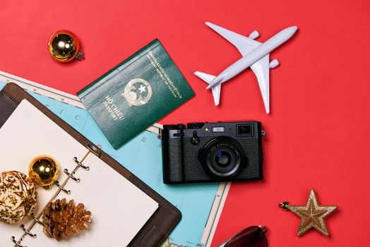 Preparation for travel concept - passport, camera, hat, airplane, chrismas decorations on red background