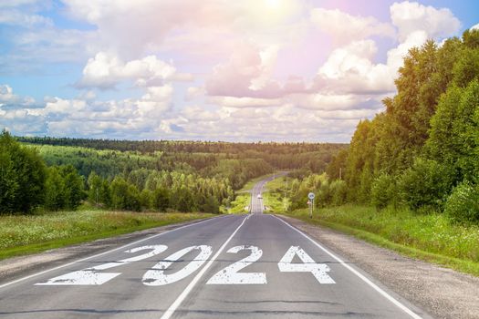 2024 written on highway road in the middle of empty asphalt road and beautiful blue sky. Concept for vision new year 2024.