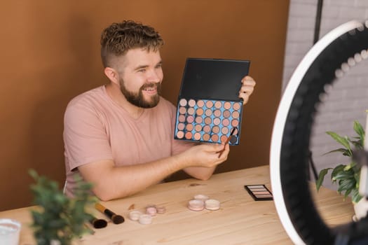 Famous blogger. Cheerful male vlogger showing cosmetics products while recording video and giving advices for his beauty blog. Make-up artist and recording beauty vlog concept
