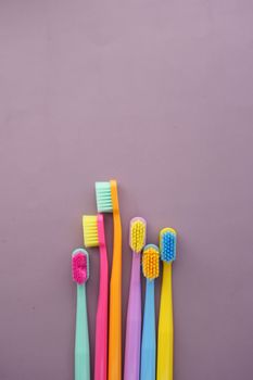top view of colorful toothbrushes on purple background