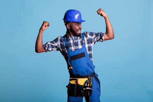 Funny construction worker showing arm muscles