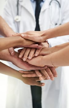 Saving lives is a team effort. a group if unidentifiable doctors stacking their hands on top of each other.