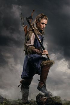Beautiful female viking woman warrior in battle with ax and bow with arrows. Amazon fantasy blonde