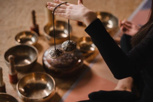 Close-up of a woman's hand holding Tibetan bells for sound therapy. Tibetan cymbals