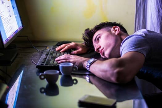 Tired man lying on table in front of computer