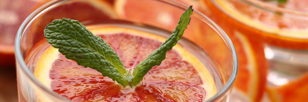 Preparation of chilled orange punch with mint homemade cocktail closeup