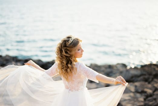 Bride stands with her arms outstretched with the overskirts of her dress
