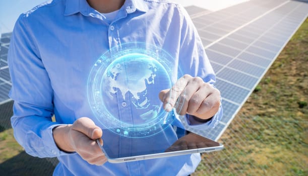 Unrecognizable engineer with a tablet with earth HUD hologram in photovoltaic solar panels plant.