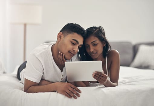 What are we going to watch today. a young couple using a digital tablet at home.