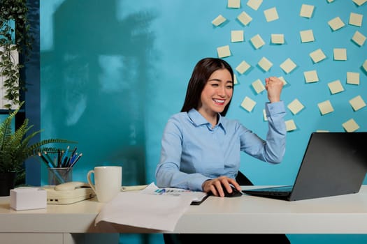 Optimistic asian woman celebrating project result