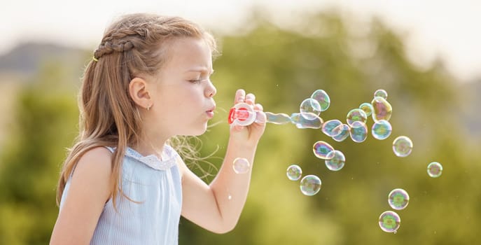 Pretty bubbles floating in the air. a little girl blowing bubbles in a park.