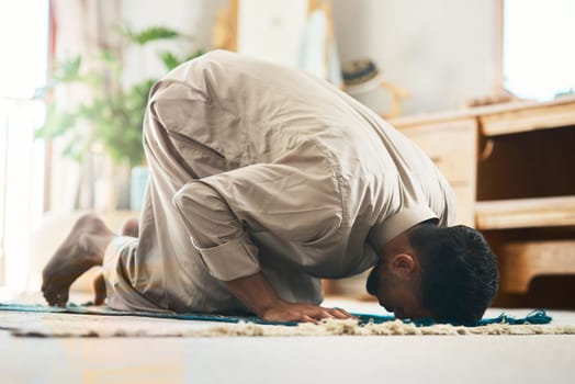 Seek and you will find. a young muslim man praying in the lounge at home.