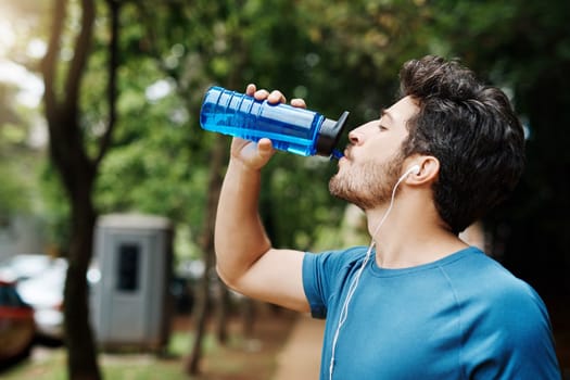 Nothing like water to refuel the engine. a sporty young man drinking water out of a bottle after having a jog outside during the day.