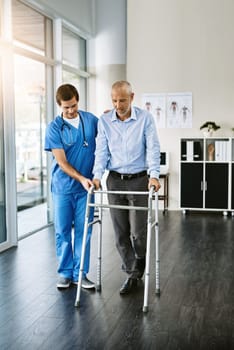 Easy does it. a male nurse assisting a senior patient with a walker.