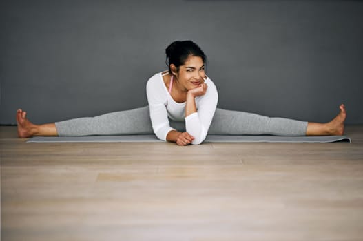 Targeting full leg flexibility with the splits. Portrait of an attractive young woman doing the splits in her yoga routine.