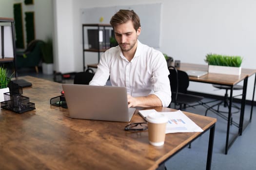 young businessman man in a white shirt works on laptops in the office
