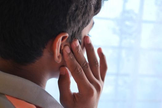 teenage boy having ear pain touching his painful ear ,
