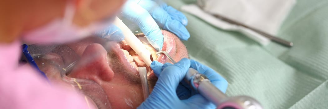 Patient with dentist checks teeth and drills tooth with caries