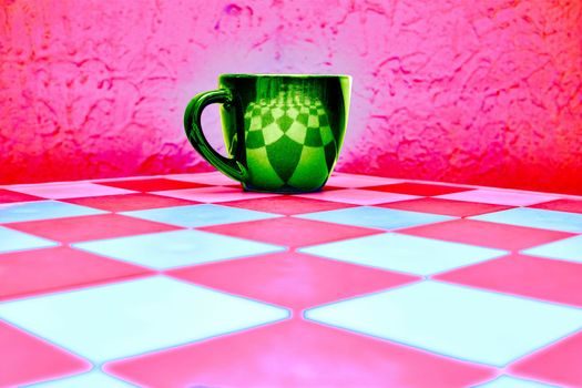 Green cup on white pink chess board and pink red abstract background
