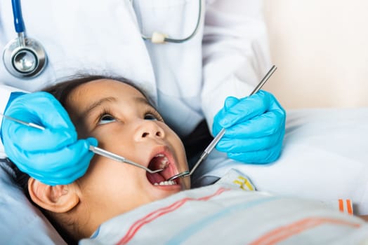 Doctor examines oral cavity of little child uses mouth mirror to checking teeth cavity