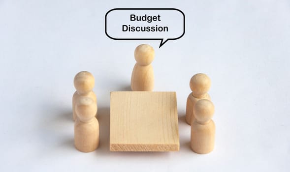 Wooden people figures having budget discussion meeting. Budgeting concept