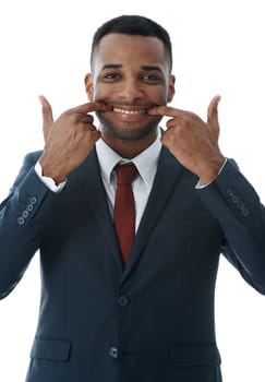Putting on a positive face. A young businessman stretching his mouth into a smile while isolated on white