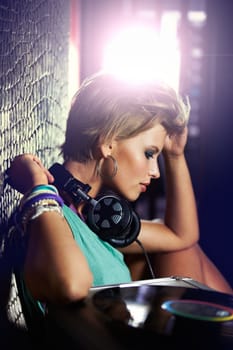 Listening to her own beats. A young female dj listening to some mixes on her headphones.