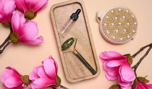 Glass bottle with a pipette and a stone massager on a beige background, items for cosmetic procedures