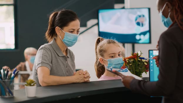 Two patients with face mask talking to facility receptionist