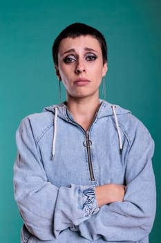 Sad miserable woman crying in front of camera having negative displeased expression while posing in studio