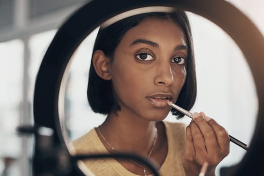The beauty guru everyone should have bookmarked on their browser. a young woman applying makeup while filming a beauty tutorial at home