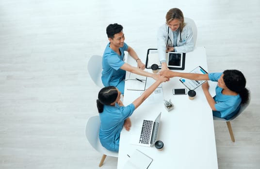 We have a plan of action. High angle shot of a group of doctors stacking their hands while in a meeting at a hospital.
