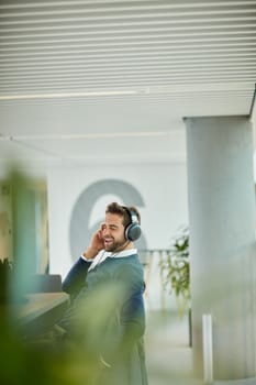 Music keeps him entertained. a young businessman listening to music in an office