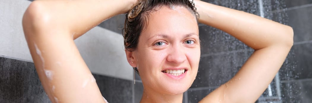 Young beautiful woman under the shower in bathroom. Portrait of happy joyful woman in the shower