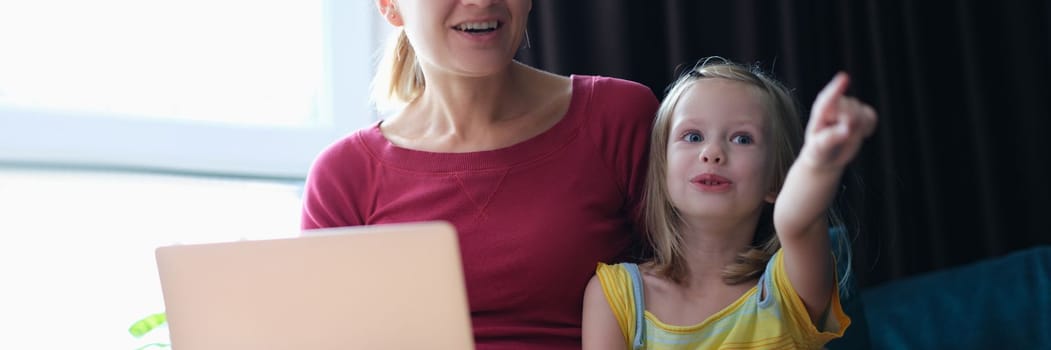 Portrait of mother and child sitting on sofa with laptop looking away in surprise