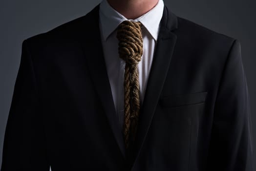 Bound by business. Cropped studio shot of a businessman with a noose tied around his neck for a tie against a gray background.