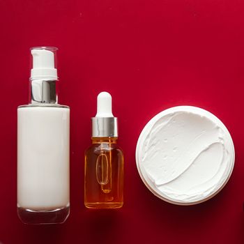 Beauty cosmetics and skincare product on red background, flatlay