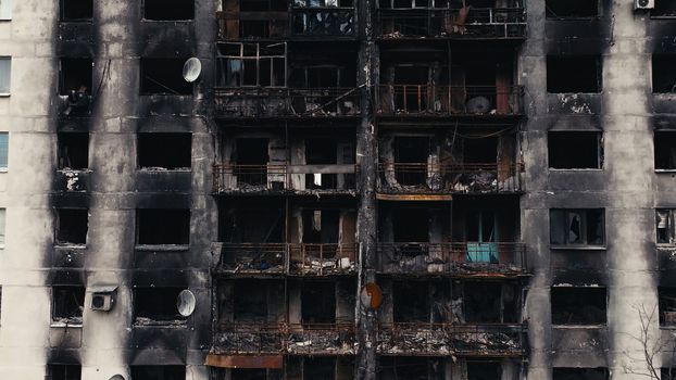 A burnt-out high-rise in the war zone. Damage to a residential building as a result of artillery shelling. War in residential areas, broken windows and burned apartments. Armed conflict in Ukraine