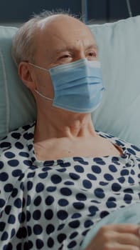 Portrait of unwell patient in hospital ward bed