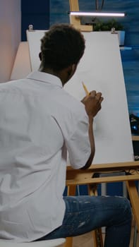 African american artist working on white canvas with drawing